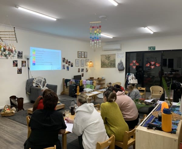 A group of staff members sit down and look at a projector in a daycare room