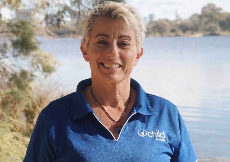 A woman smiles with a lake behind her