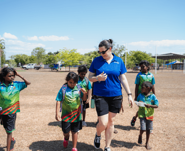 An educator and 5 children walk along the grass and talk