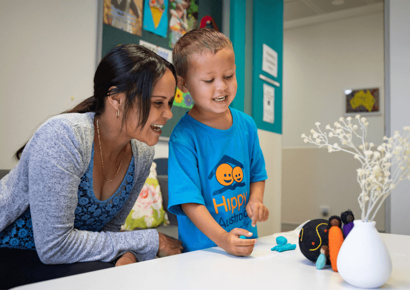 A woman and a child smile together and play with playdoh