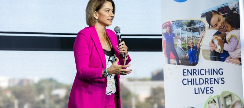 A woman speaks to an audience through a microphone
