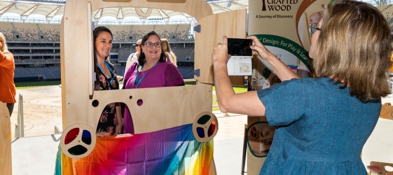 A woman takes a photo of two friends at an event