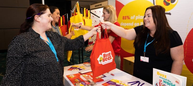 A woman hands out a 'Busy Bees' bag