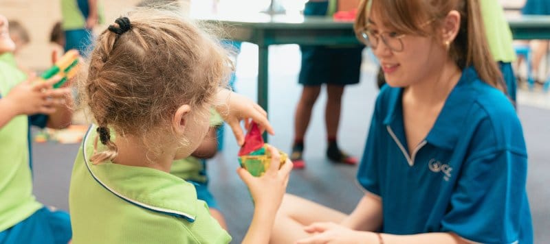 An educator and a child play with blocks together